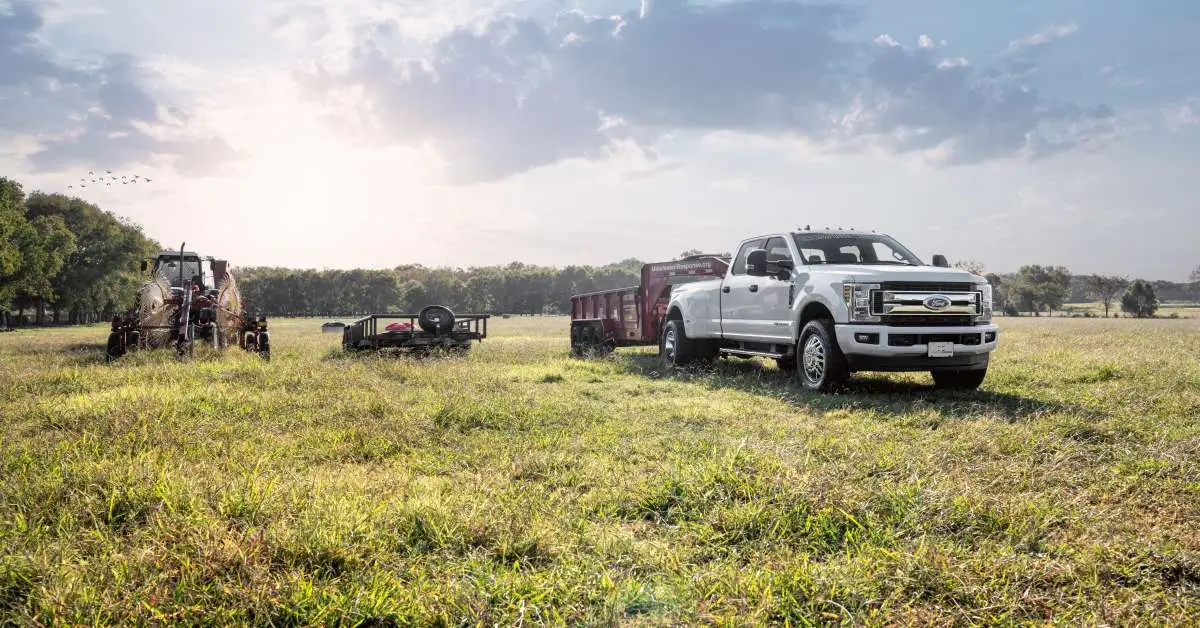 Pickup truck with gooseneck trailer and farm equipment in a field